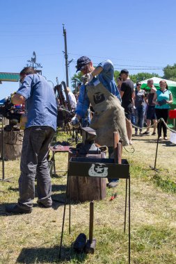 Genç bir adam sanatı deneyimli demirci öğretir