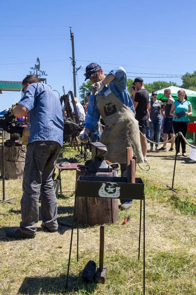 Genç bir adam sanatı deneyimli demirci öğretir