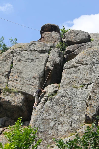 女性ロッククライマーが岩の上に登る — ストック写真