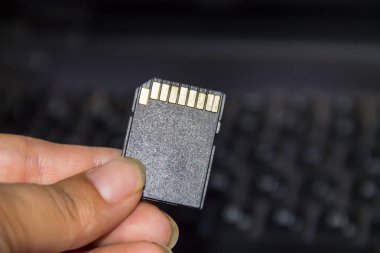 SD kartı laptop arka planda tutan el