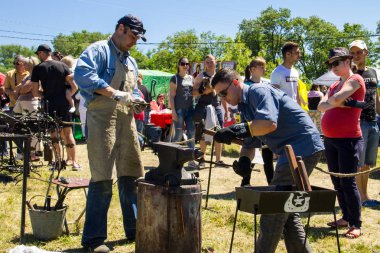Genç bir adam sanatı deneyimli demirci öğretir