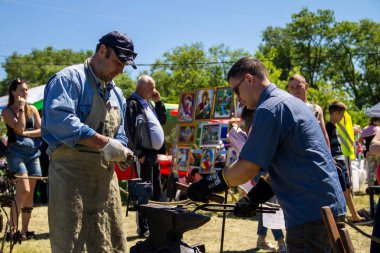 Genç bir adam sanatı deneyimli demirci öğretir