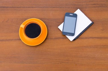 Smartphone, not defteri ve kalem ahşap masa kahve fincanı 