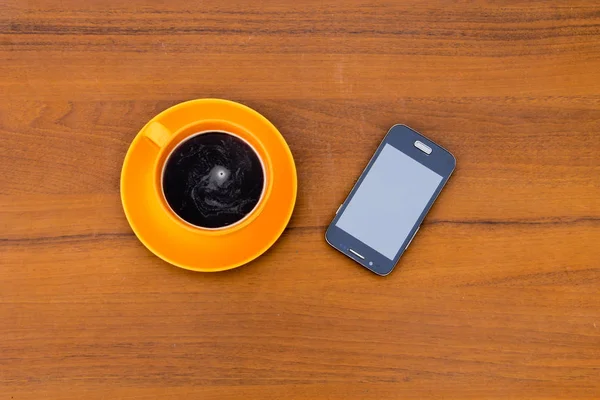 Fincan kahve ve ahşap masa üstünde smartphone