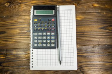 Kalem ve ahşap masa hesap makinesi ile not etmek