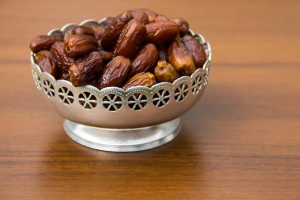Dates fruit on a silver bowl on wooden table — Stock Photo, Image