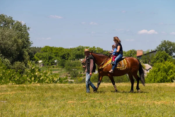 Hombre liderando un caballo con una mujer joven y su hijo montar — Foto de Stock