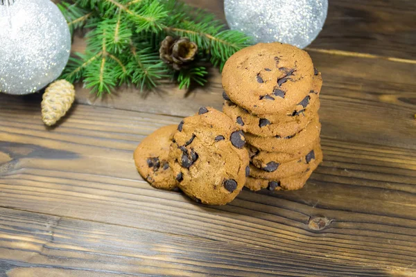 Biscoitos de chocolate na frente da decoração de Natal na mesa de madeira — Fotografia de Stock