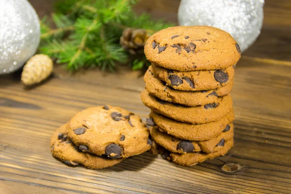 Chocolate chip cookies in front of Christmas decoration on wood table — Stock Photo, Image