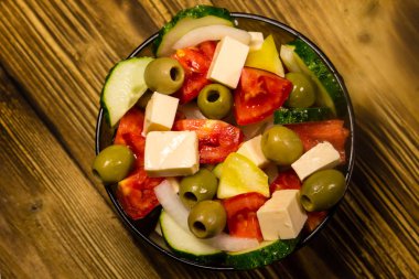 Ahşap masa üzerinde cam kapta Yunan salatası