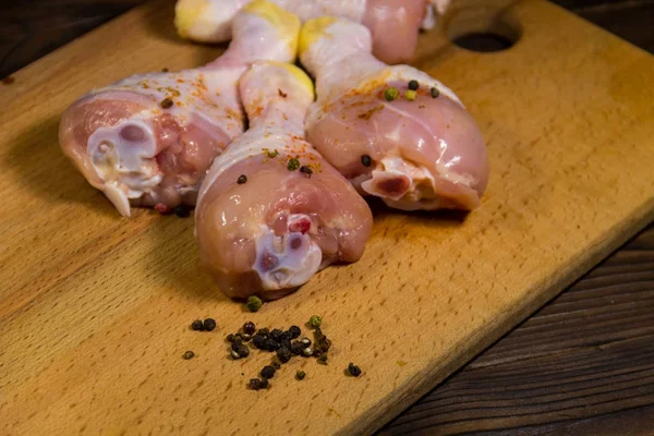 Pernas de frango cru com especiarias na mesa de madeira — Fotografia de Stock