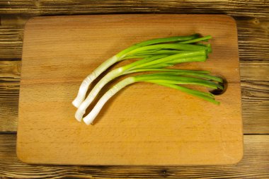 Ahşap masa üzerinde kesme tahtası üzerinde taze yeşil soğan