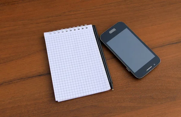 Kalem ve ahşap masa üzerinde smartphone ile not etmek