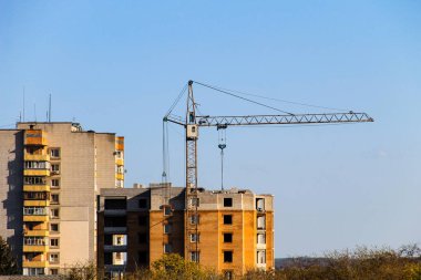 Mavi gökyüzüne karşı inşaat halindeki vinç ve bina