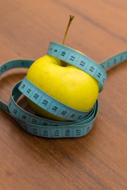 Ölçüm bandı ve ahşap masa üzerinde yeşil elma. Diyet kavramı 