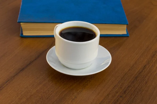 Taza de café y libro sobre mesa de madera — Foto de Stock