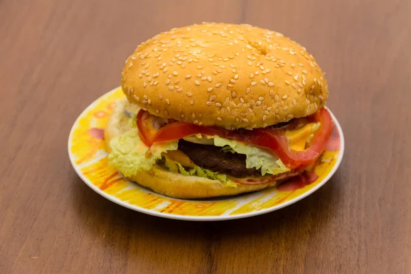 Läcker hamburgare eller smörgås på plattan på träbord — Stockfoto