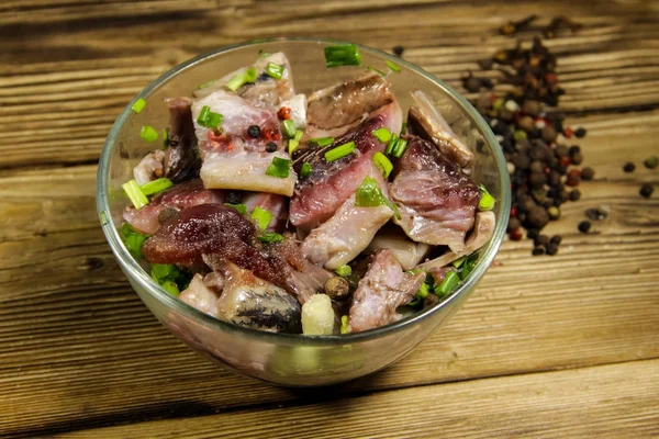 Deliziosa aringa salata con spezie in ciotola di vetro sul tavolo di legno — Foto Stock