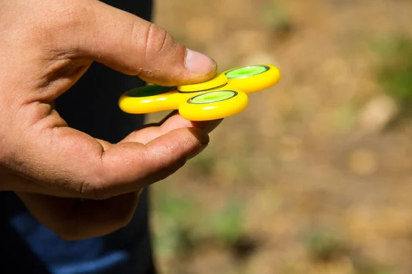 Man playing with fidget spinner stress relieving toy outdoor