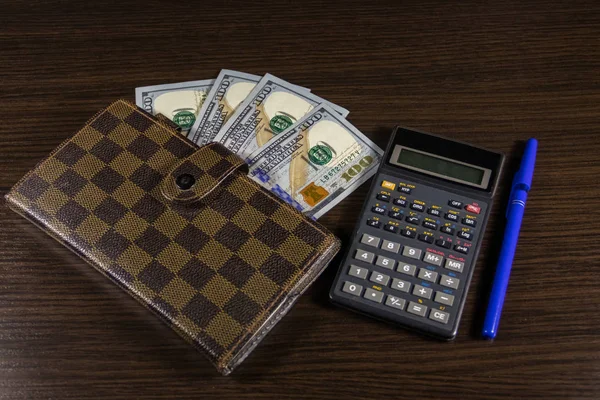 Cuaderno con dólares, pluma y calculadora en el escritorio de la oficina — Foto de Stock