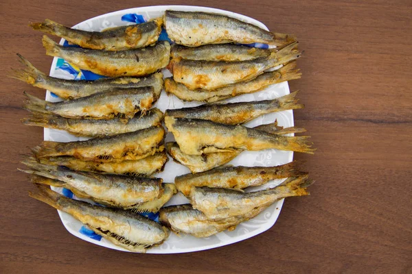 Arenque báltico frito en un plato sobre fondo de madera — Foto de Stock