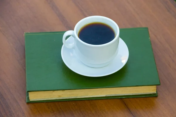 Xícara de café e livro em mesa de madeira — Fotografia de Stock