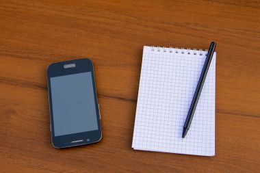 Kalem ve ahşap masa üzerinde smartphone ile not etmek