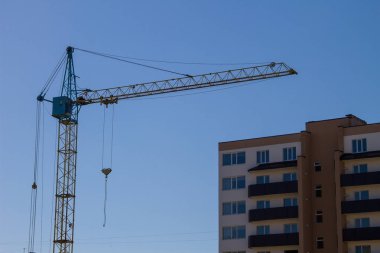 Mavi gökyüzüne karşı inşaat halindeki vinç ve bina