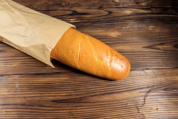 Baguette francesa en bolsa de papel sobre mesa de madera — Foto de Stock