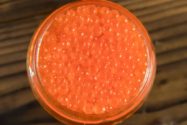 Caviar vermelho em frasco de vidro na mesa de madeira — Fotografia de Stock