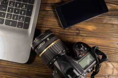 Dizüstü bilgisayar, akıllı telefon ve ahşap arka plan üzerinde fotoğraf makinesi