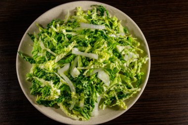 Ahşap masada lahana ve soğanlı salata.