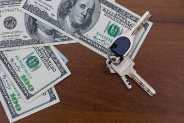 Anahtarları ve Amerikan yüz dolar faturaları ahşap masa
