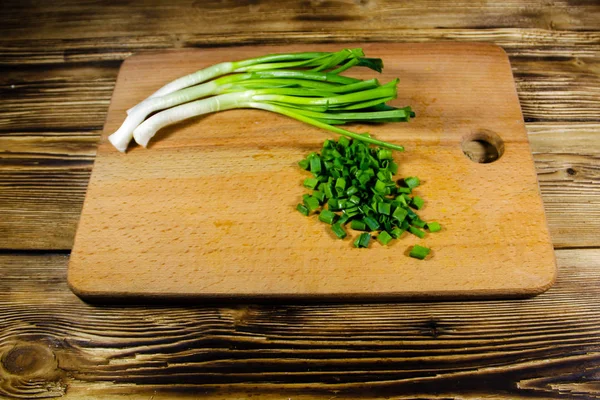 Chopped green onions on cutting board on wooden table — Stock Photo, Image