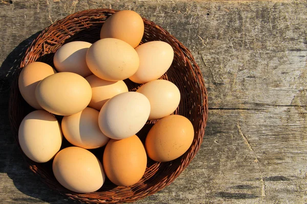 Eggs in wicker basket on wooden table — Stock Photo, Image