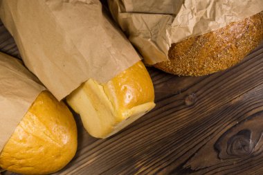 Kağıt ahşap masa üzerinde paketlenmiş ekmek çeşitleri