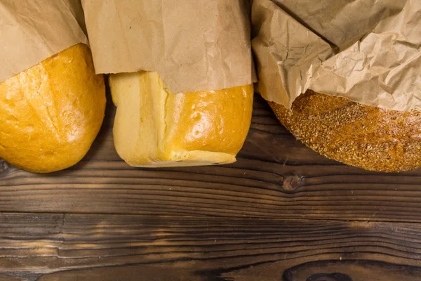 Assortment of bread packed in paper on wooden table