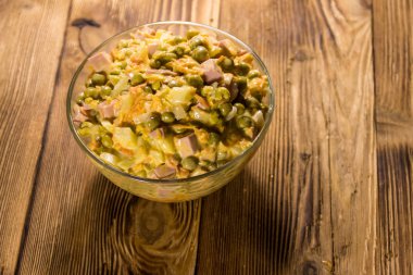 Sosis, bezelye, havuç ve soğan ahşap masa üzerinde mayonez salatası