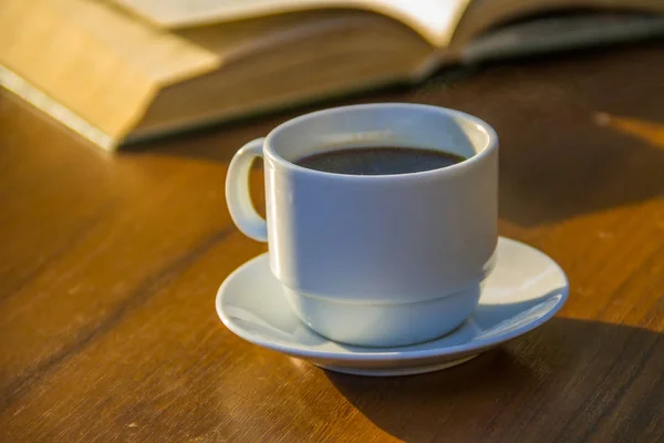 Bir fincan kahve ve kitap ahşap masada. — Stok fotoğraf