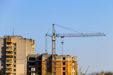 Mavi gökyüzüne karşı inşaat halindeki vinç ve bina