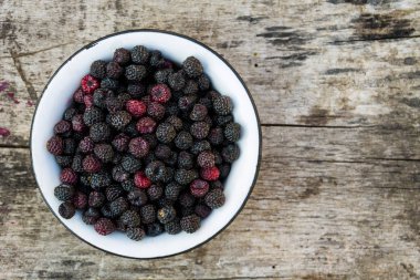 Eski ahşap arka plan üzerinde rustik kase olgun böğürtlen