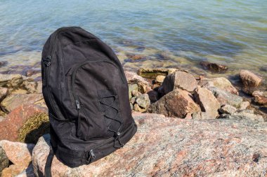 Deniz kıyısında arka plan ile kayaya sırt çantası