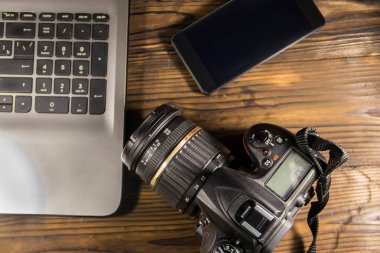 Dizüstü bilgisayar, akıllı telefon ve ahşap arka plan üzerinde fotoğraf makinesi