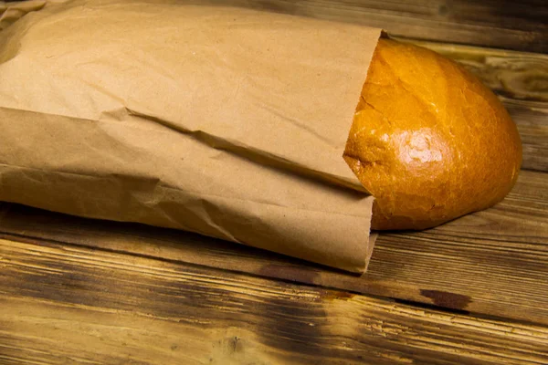 Bread packed in paper on wooden table