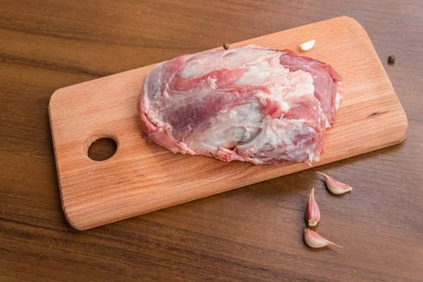 Сырое мясо свинины на разделочной доске на столе — стоковое фото