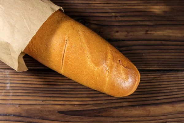 Baguette francesa en bolsa de papel sobre mesa de madera — Foto de Stock