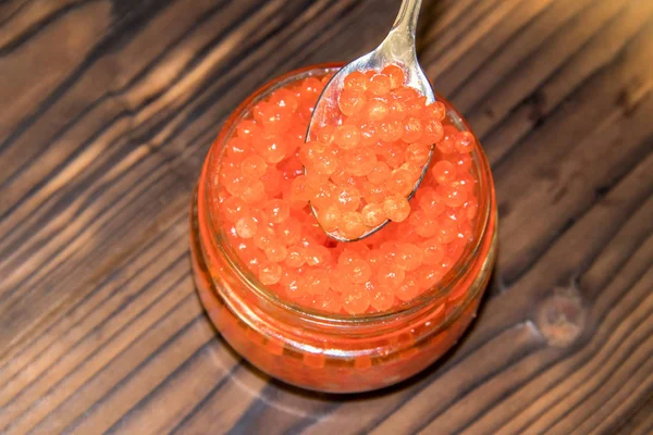 Red caviar in glass jar on wooden table — Stock Photo, Image