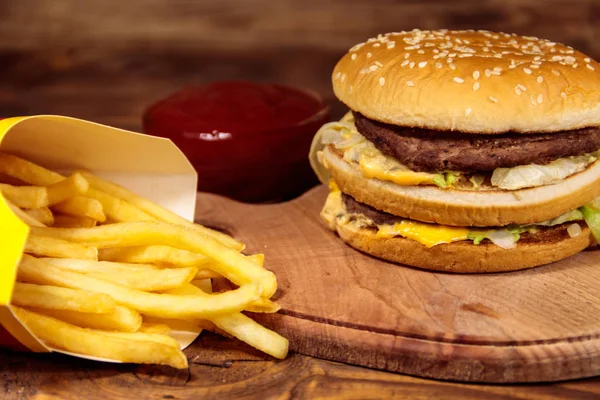 Delicioso hambúrguer grande com batatas fritas e ketchup na mesa de madeira — Fotografia de Stock