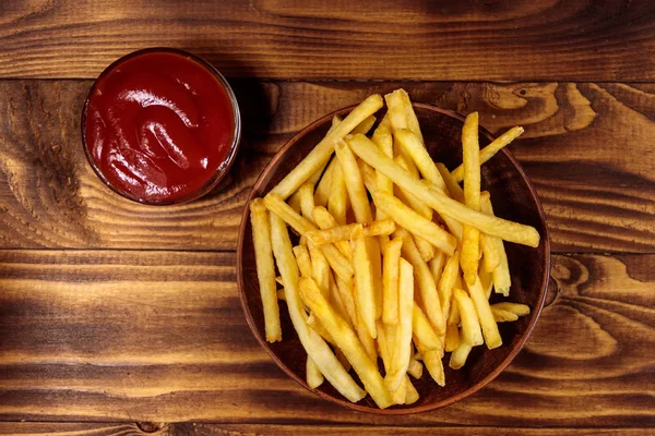 Batatas fritas com ketchup na mesa de madeira — Fotografia de Stock