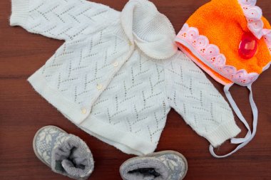 Bebek giysileri, patik ve ahşap arka plan üzerinde emzik